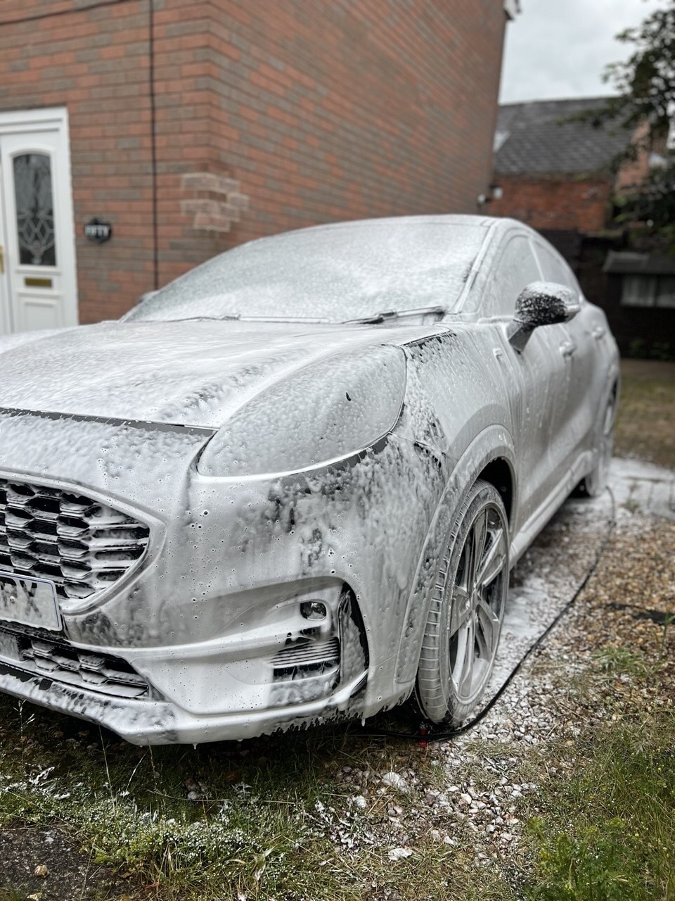 White car covered in snow foam during a mobile valet by Kaizen Cars Detailing